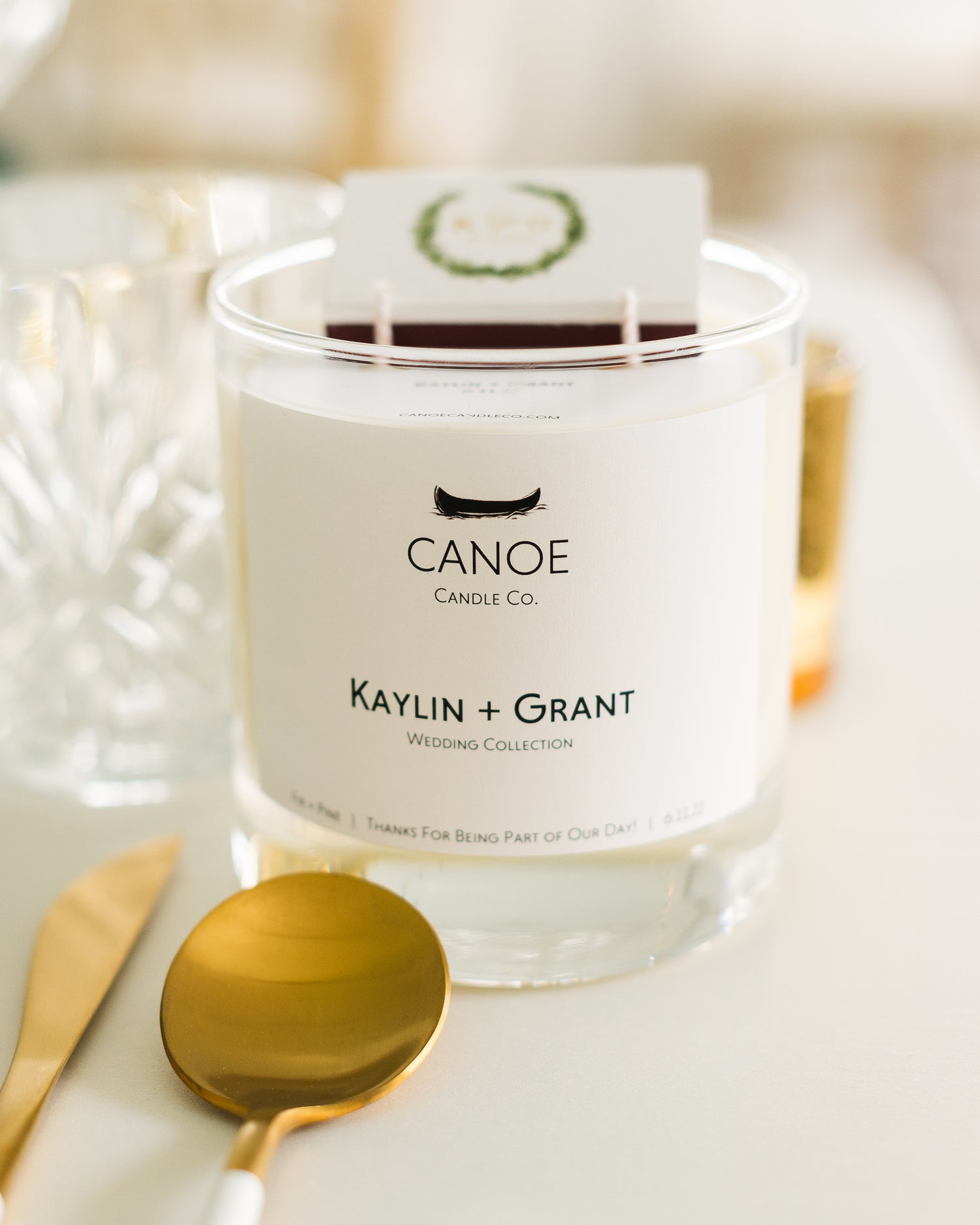 Canoe Candle Co's Canoe Custom 10oz soy wax candle on a dinner table set with gold cutlery and cut crystal glassware.