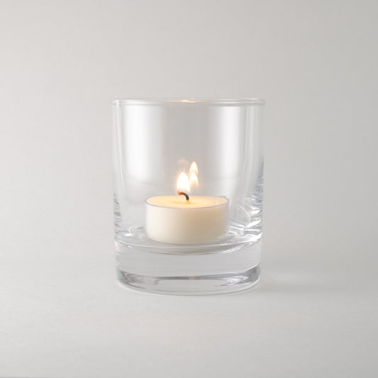 Canoe Candle Co's 7oz tealight rocks glass on plain white background with tealight burning inside it.